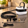 Limpiadora de vapor blanca y negra con manguera y accesorios sobre una encimera de cocina