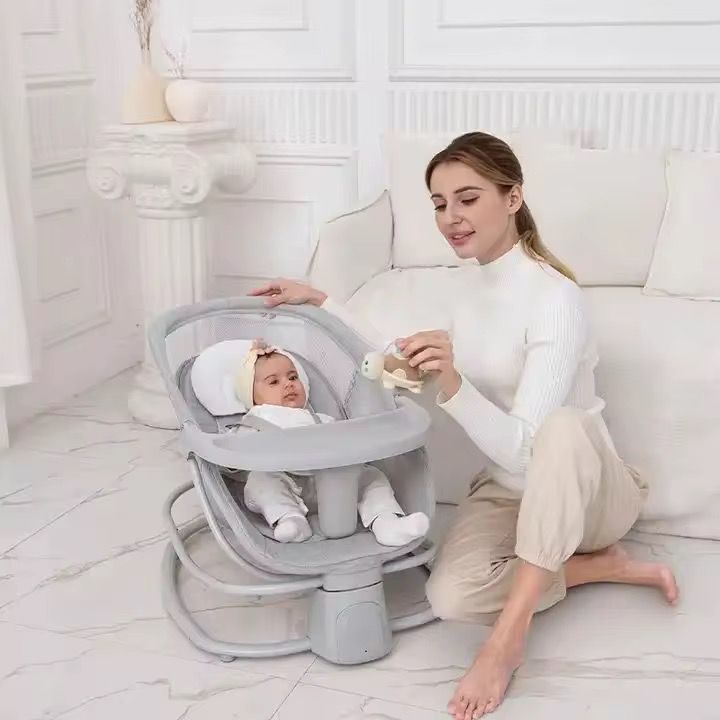 Bebé en la silla mecedora gris junto a su mamá